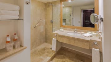 A bathroom with a glass shower enclosure, a vanity with a sink, and a mirror.