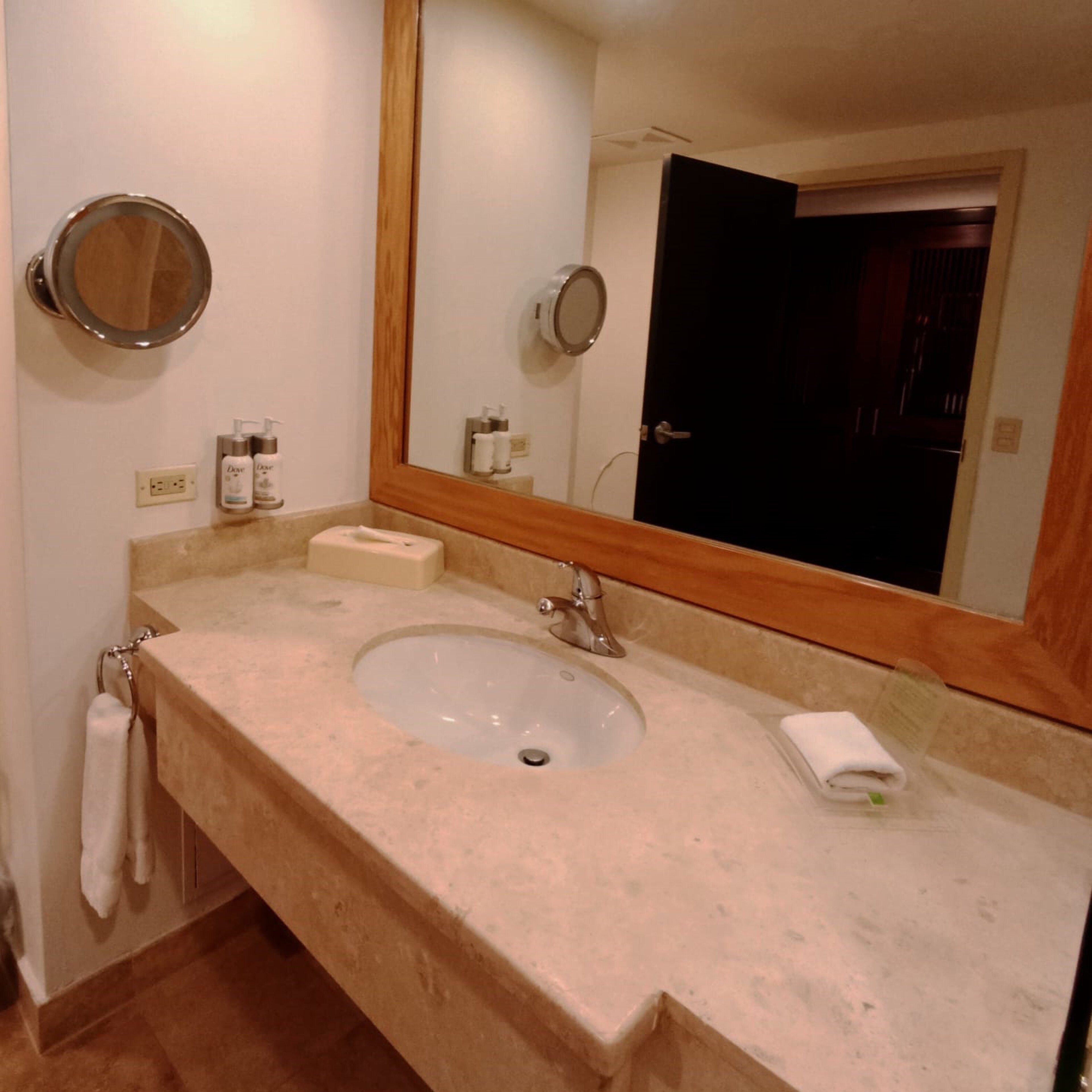 A bathroom with a sink, mirror, and toiletries.
