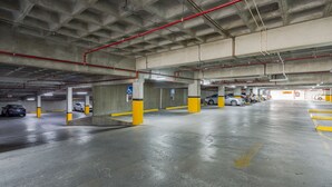 Un estacionamiento de varios niveles con pilares de hormigón y marcas de seguridad amarillas.