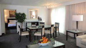 A hotel room with a bed, a desk with a chair, a dining table with chairs, a lamp, and a plant. - Holiday Inn Monterrey Valle by IHG (San Pedro Garza García)