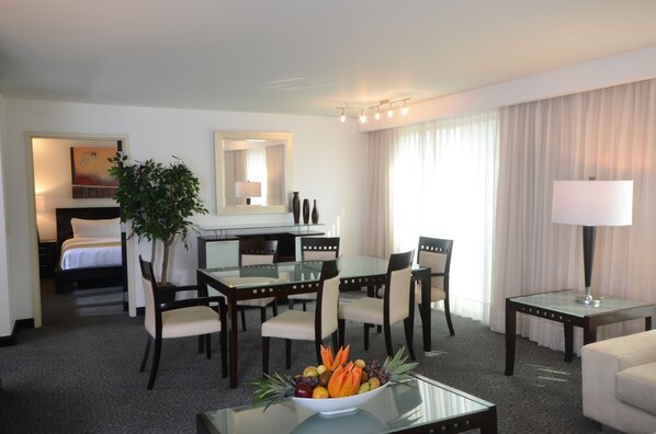 A hotel room with a bed, a desk with a chair, a dining table with chairs, a lamp, and a plant. - Holiday Inn Monterrey Valle by IHG (San Pedro Garza García)