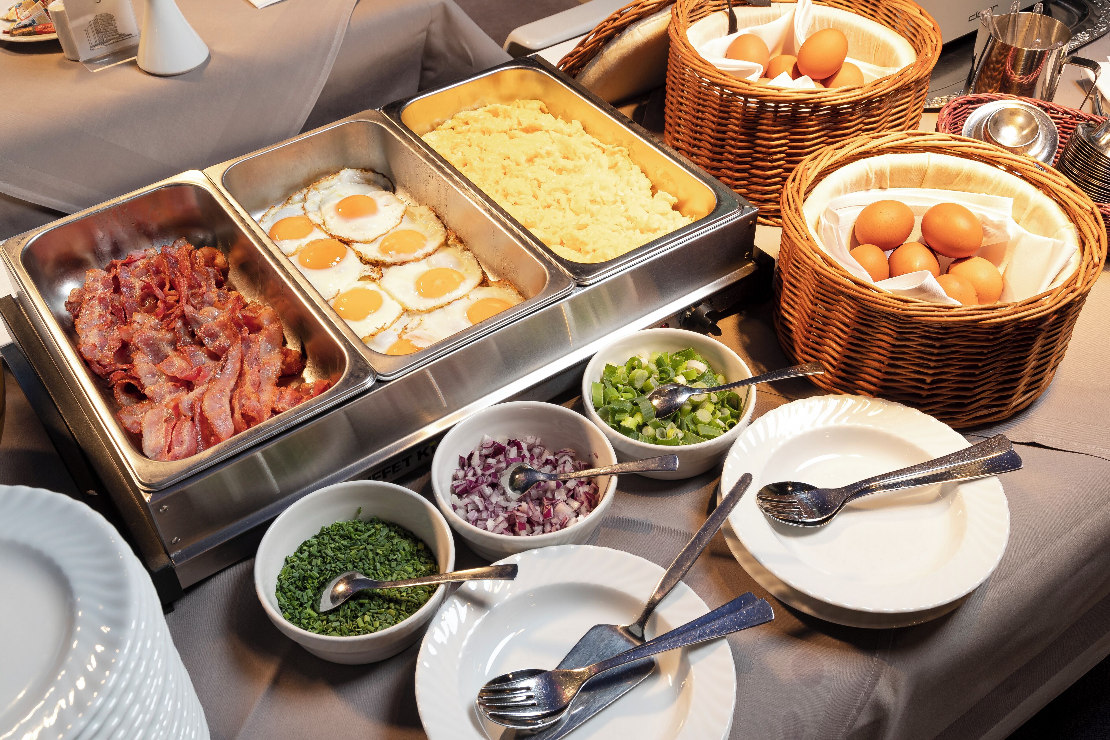 A buffet with various food items including bacon, eggs, and vegetables.
