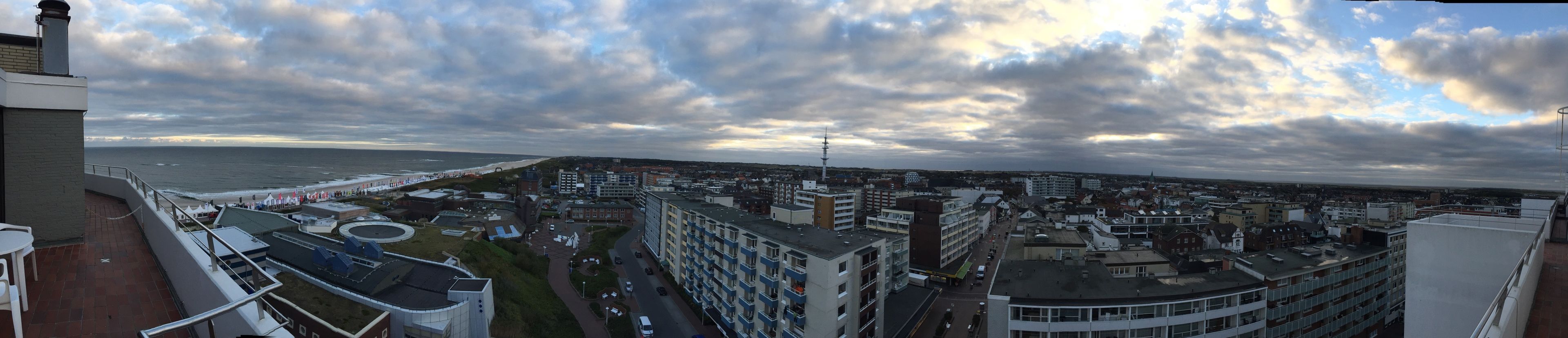 Een kuststadsgezicht met gebouwen, een strand en een bewolkte lucht.
