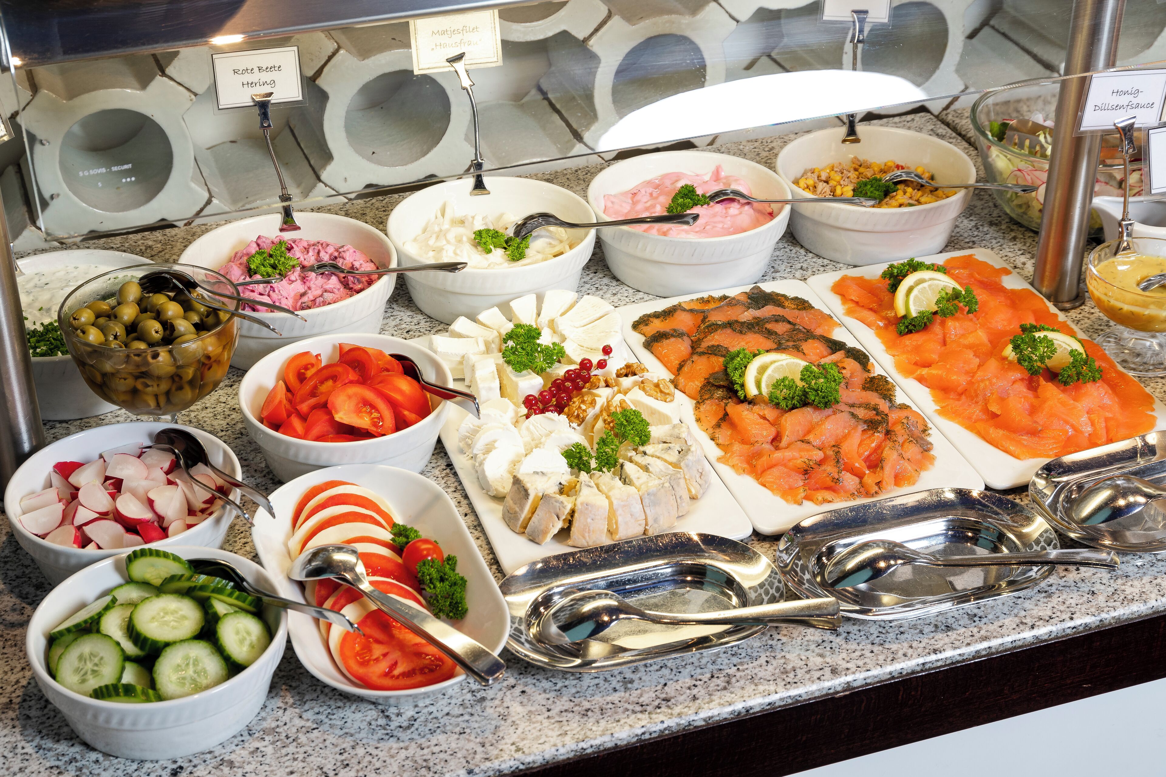 A buffet with various food items including salmon, cheese, and vegetables.