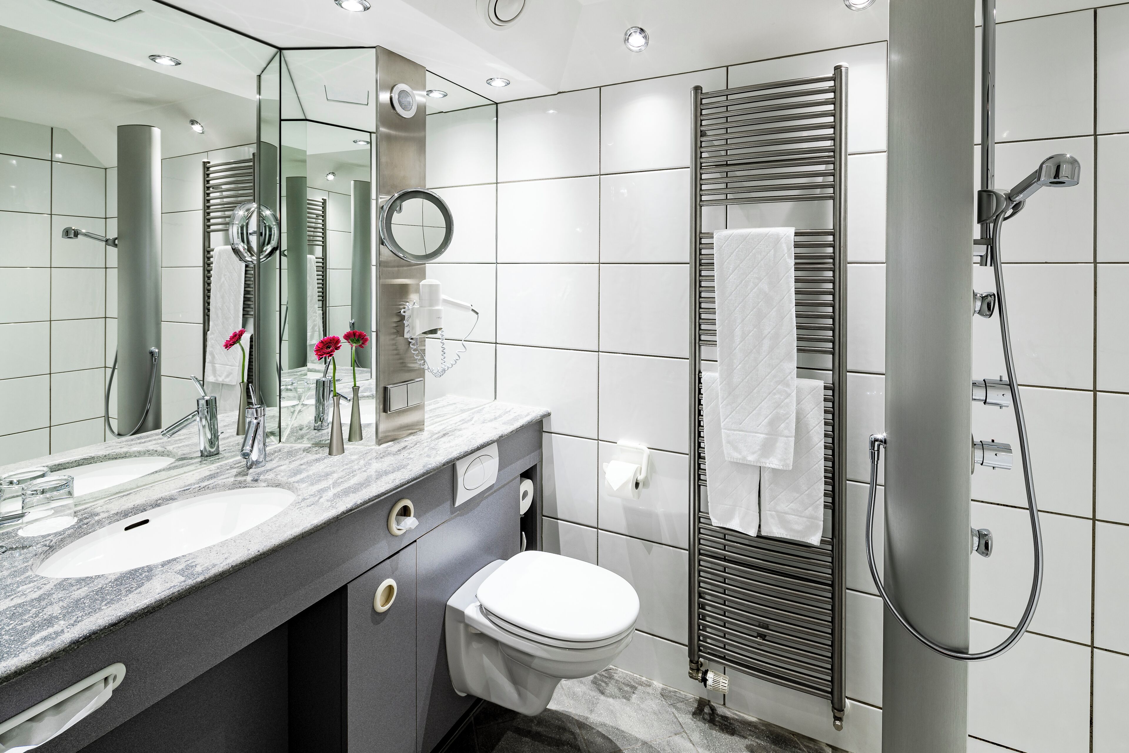 Un baño moderno con lavamanos doble, inodoro, ducha y un espejo grande.