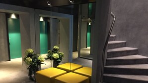 Un intérieur moderne avec un escalier, un coin salon doté de chaises jaunes et un mur vert.