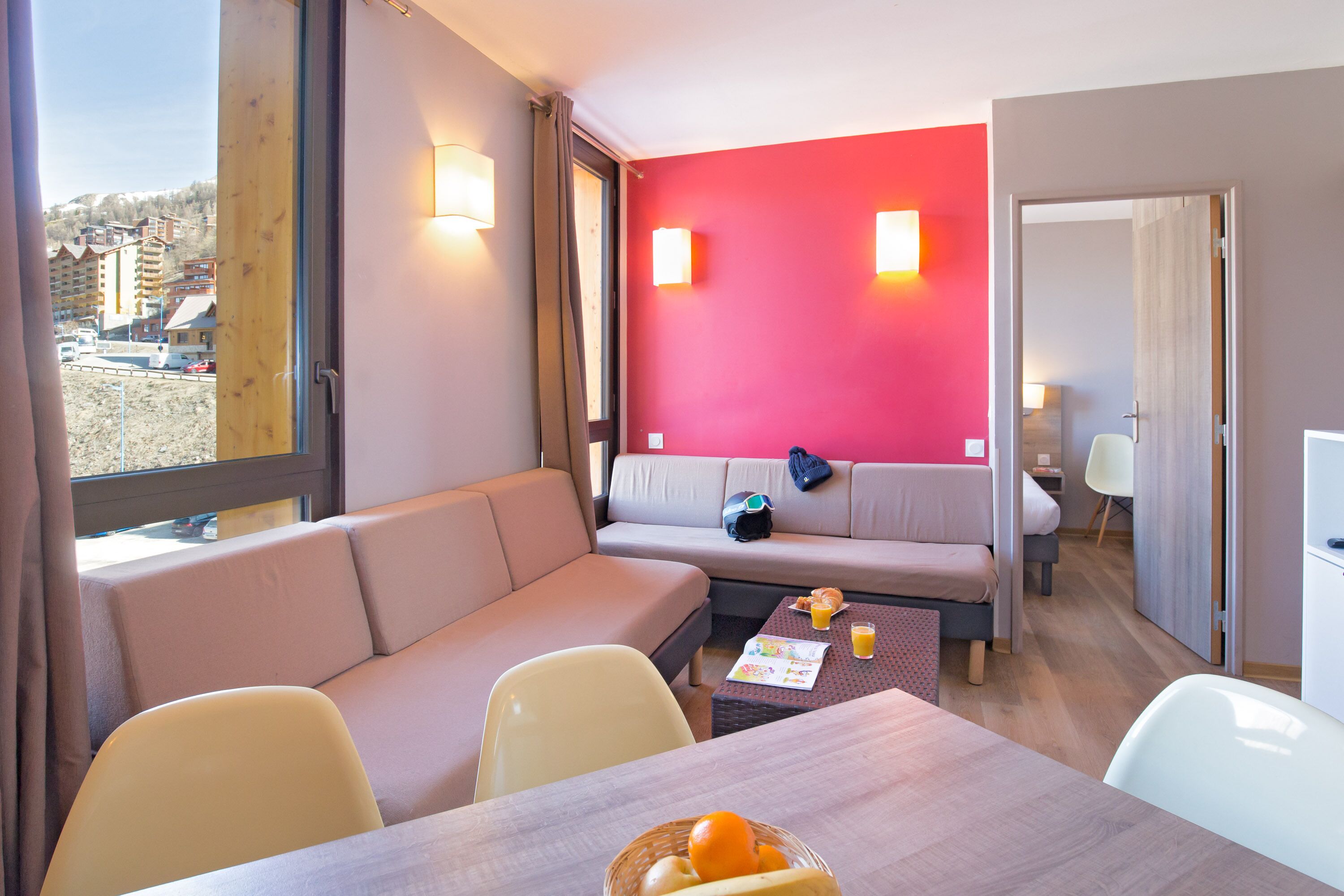 A modern living room with a sofa, a dining table with chairs, and a view of the outside.