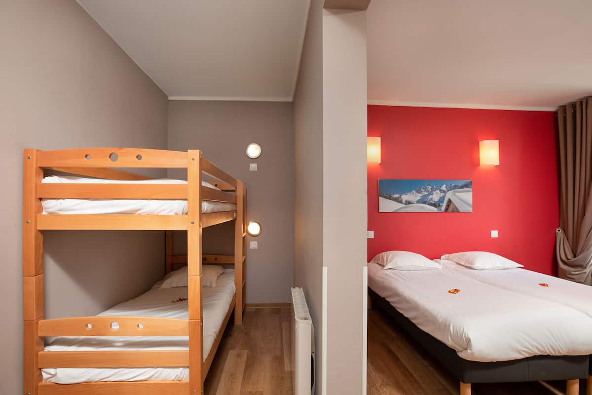 Une chambre avec un lit superposé, un lit simple, un radiateur et un tableau accroché au mur.