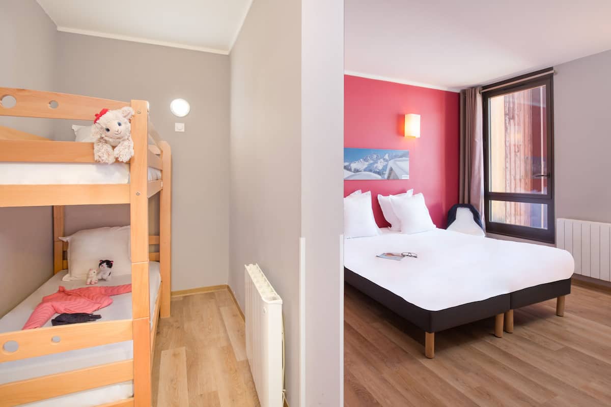 Une chambre avec un lit superposé et un lit séparé, tous deux dotés de draps blancs.