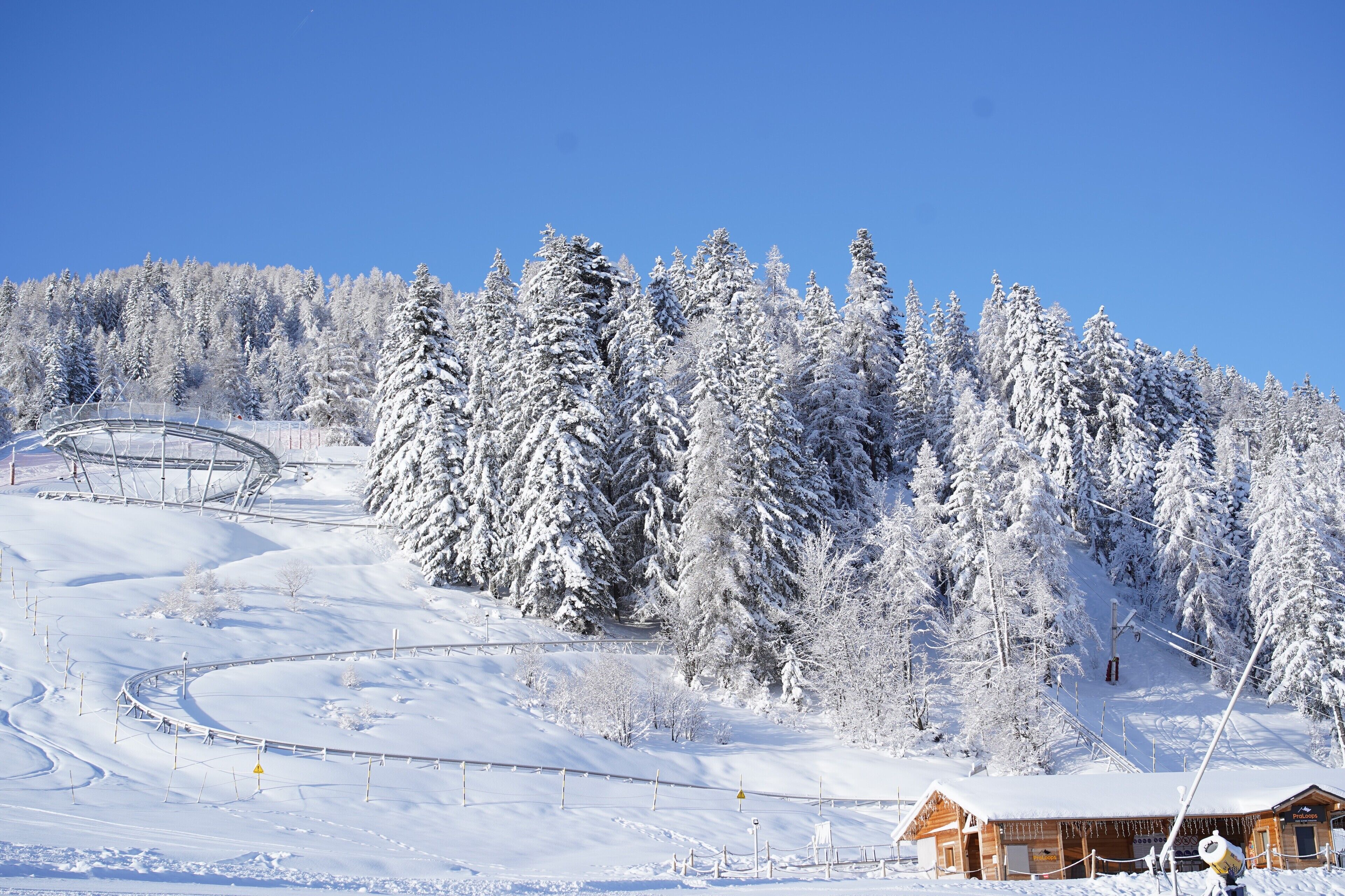 Paisaje nevado de montañas con una cabaña de madera y pistas de esquí.