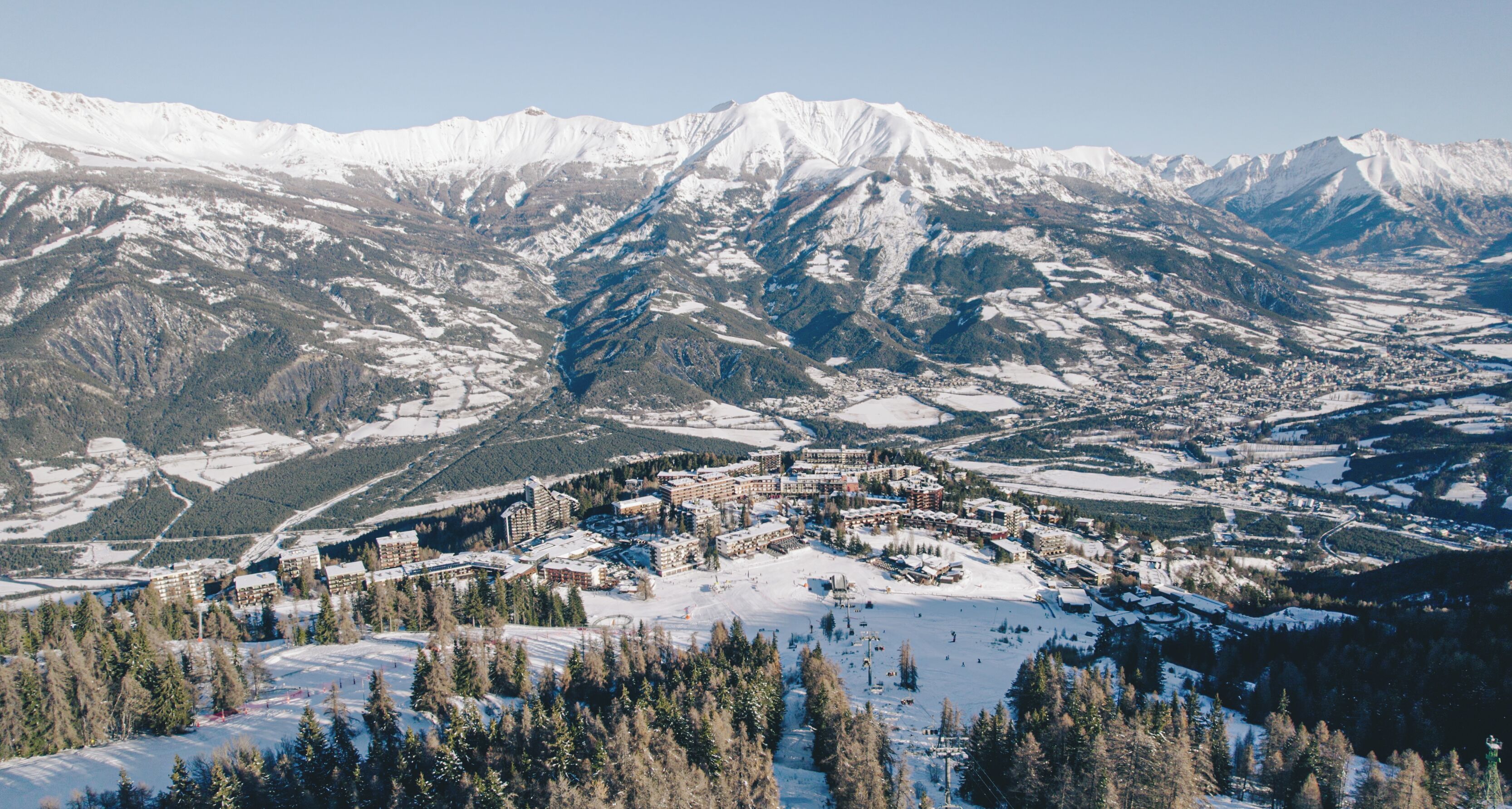A snow-covered mountain town with a ski resort, including buildings and ski slopes.