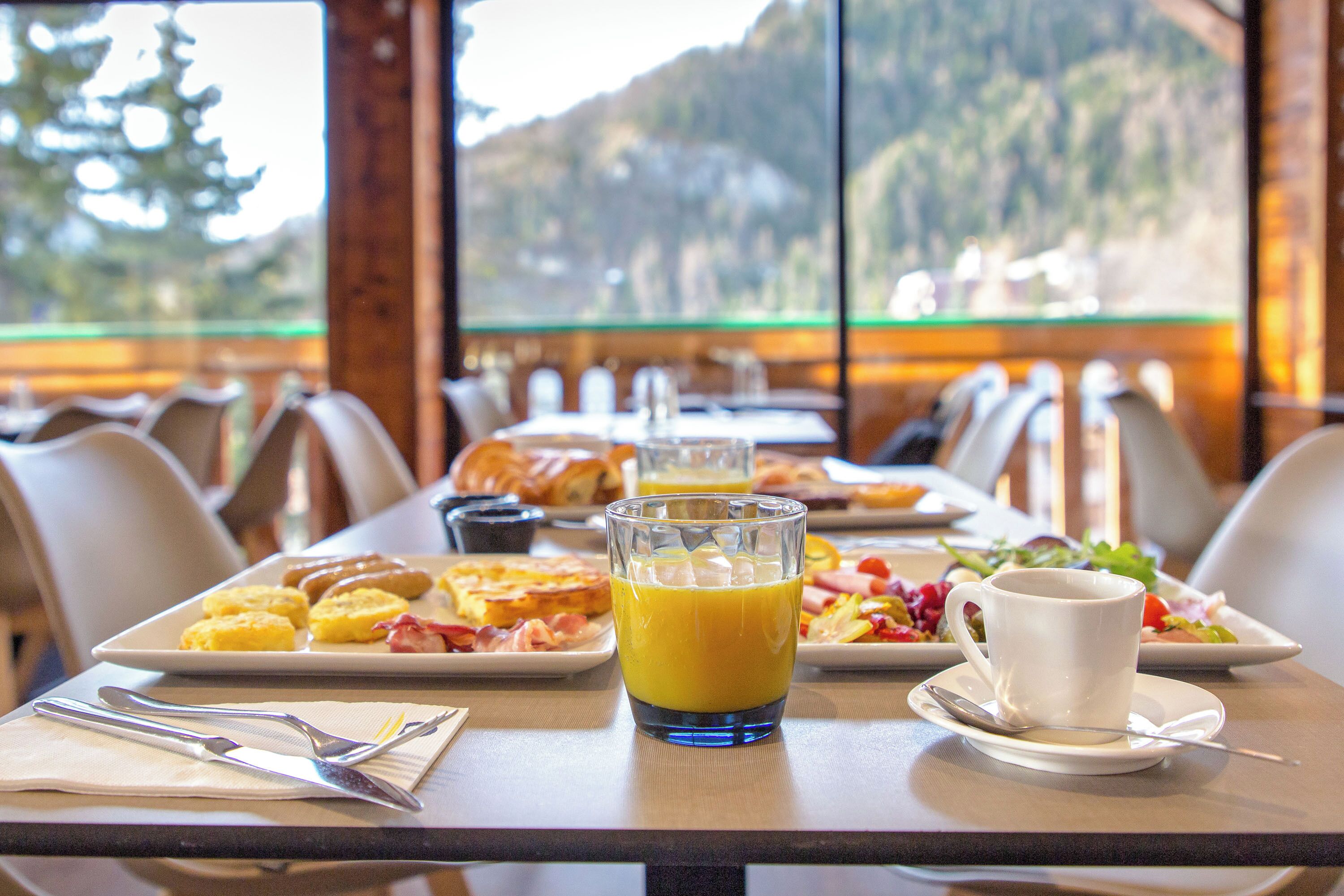 A breakfast table with plates of food, a glass of orange juice, and a cup of coffee.