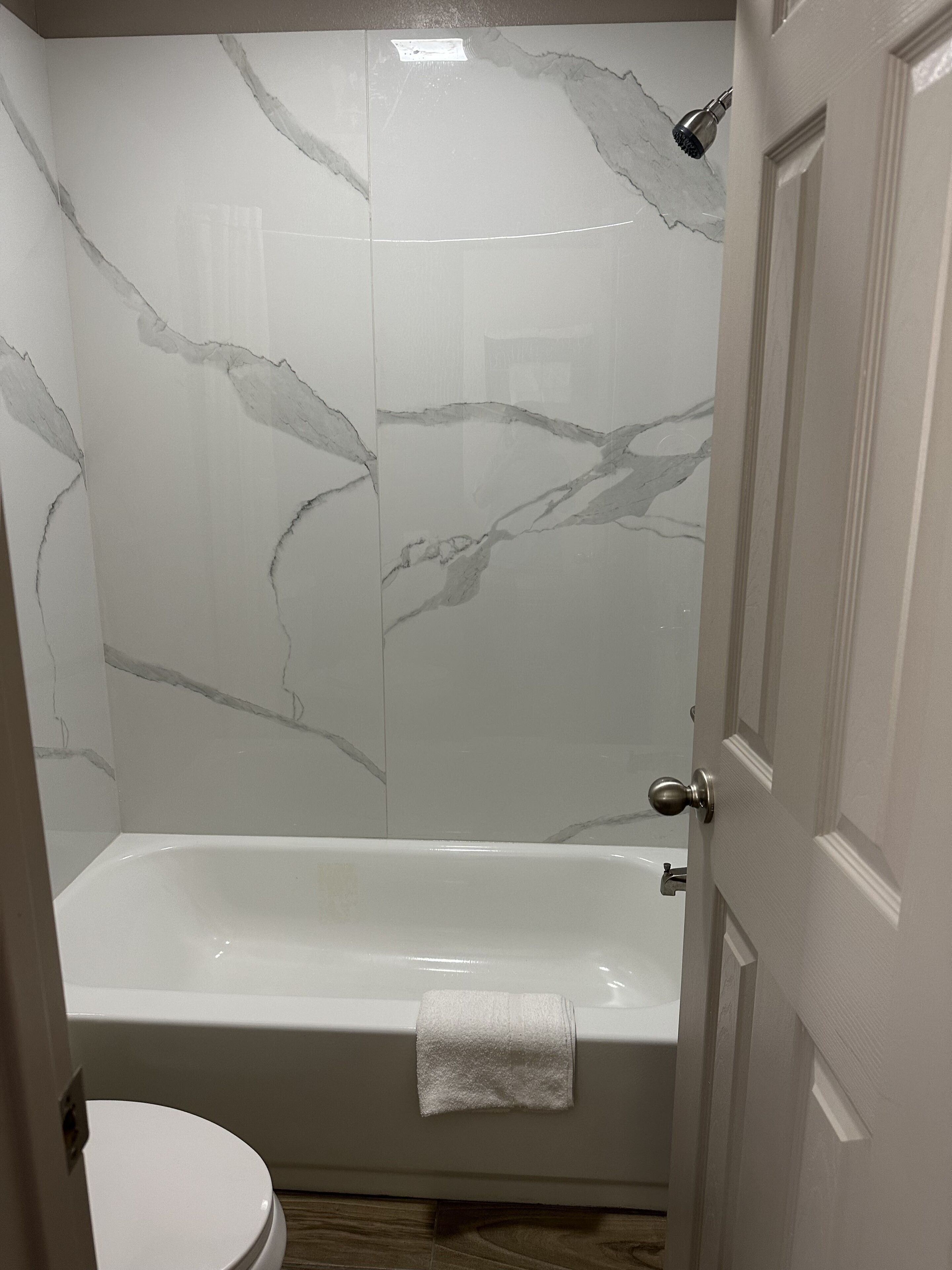 A bathroom with a bathtub, a toilet, and marble walls.
