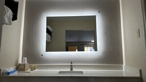 A bathroom with a large mirror, a sink, and a towel rack. - Express Inn & Suites (Hartselle)