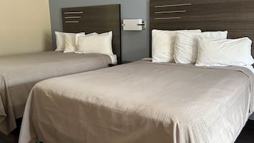 Two twin beds with headboards, a bedside table, and a wall-mounted light fixture in a hotel room.