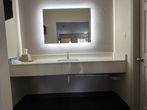 A bathroom with a mirror, sink, and toilet.