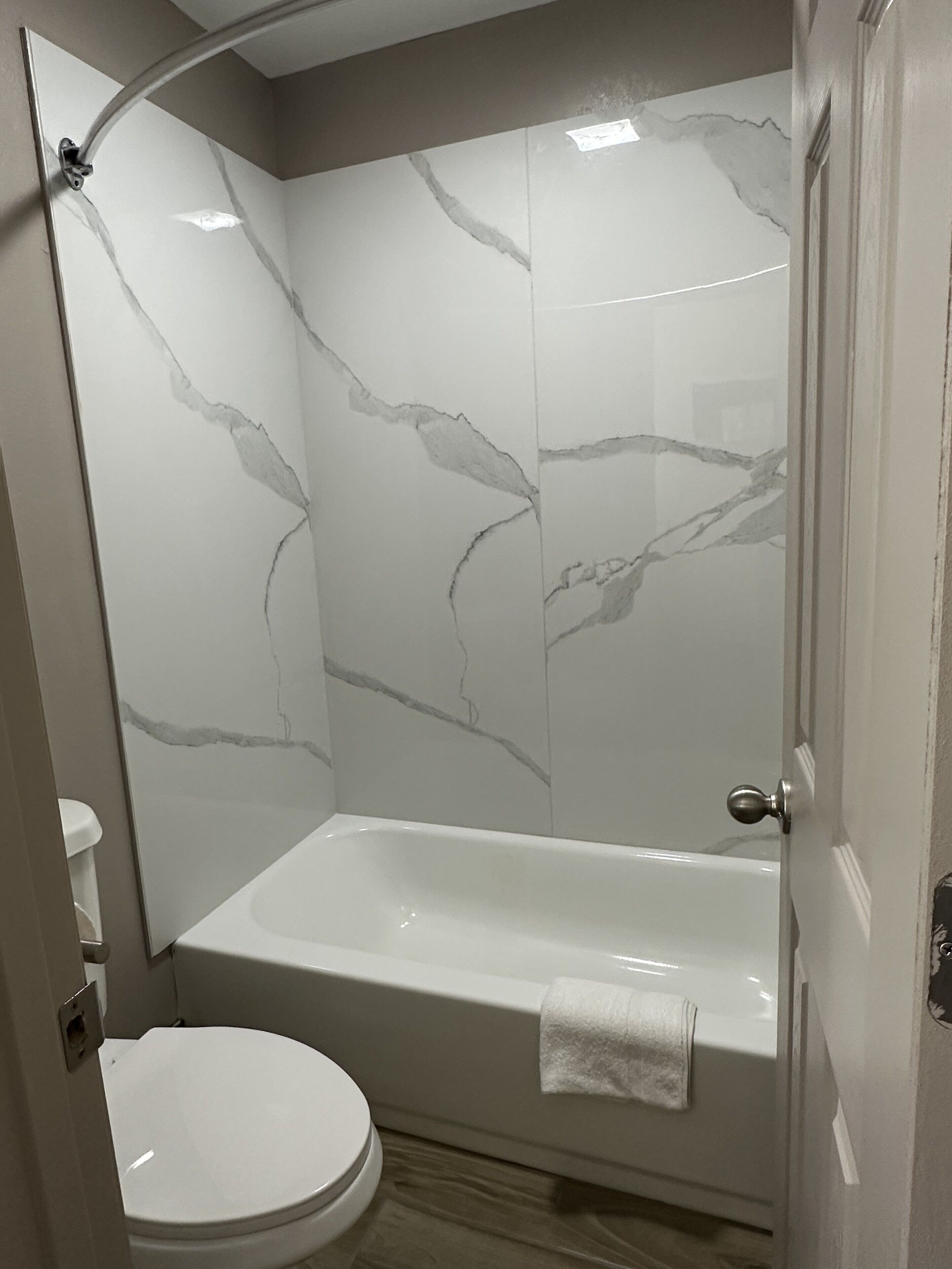 A bathroom with a bathtub, toilet, and a shower area with a glass door.