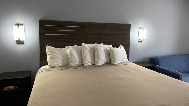 A hotel room with a large bed, a dark headboard, and two wall-mounted lights. - Express Inn & Suites (Hartselle)
