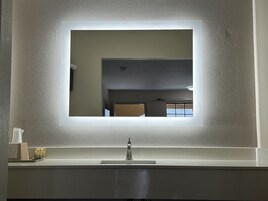 Un baño con un espejo grande, un lavabo y un dispensador de toallas.
