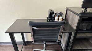 A black office chair with a high backrest and a metal base, positioned on a dark wooden floor. - Express Inn & Suites (Hartselle)