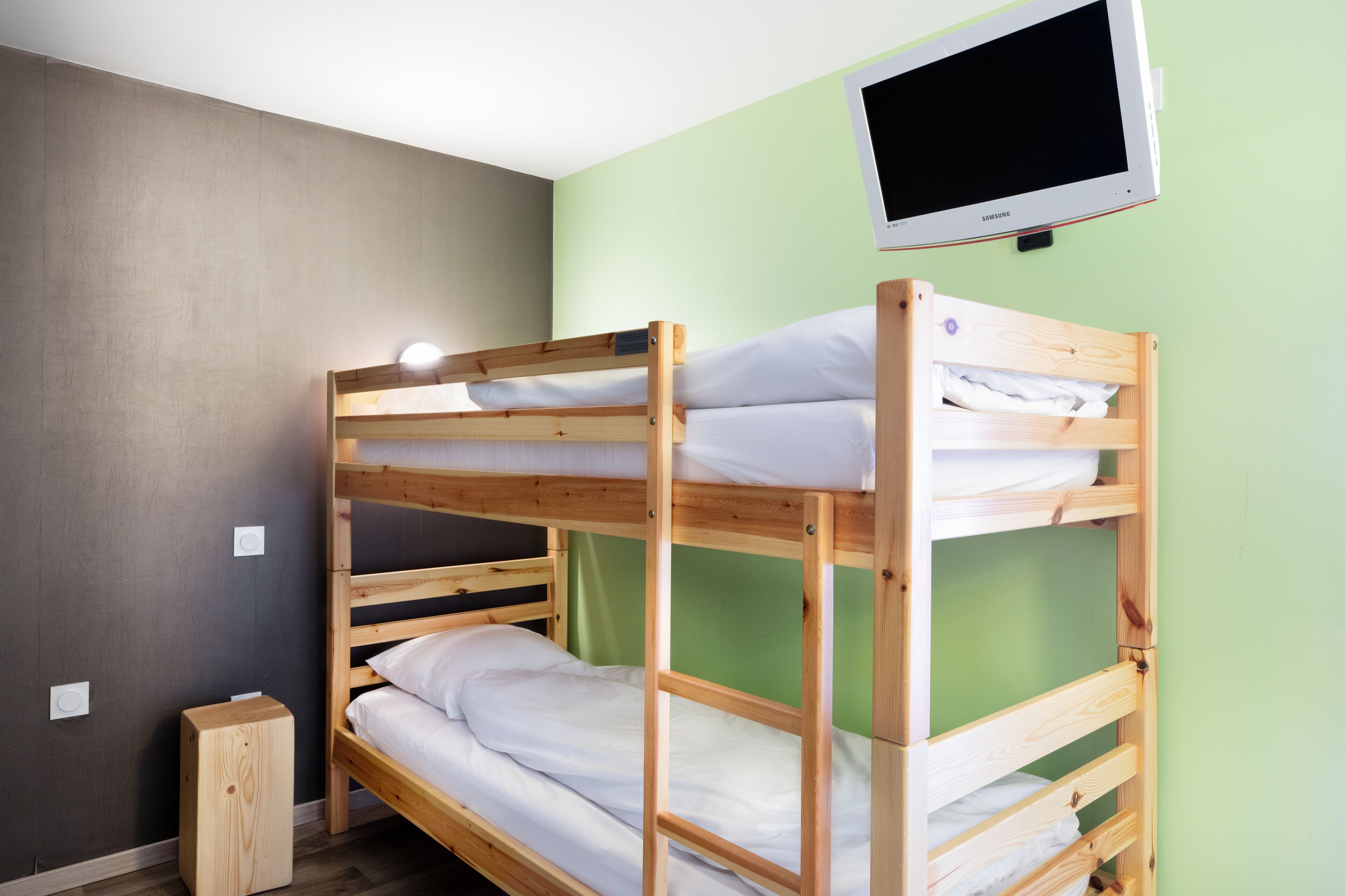 A bunk bed with a television mounted on the wall above it.