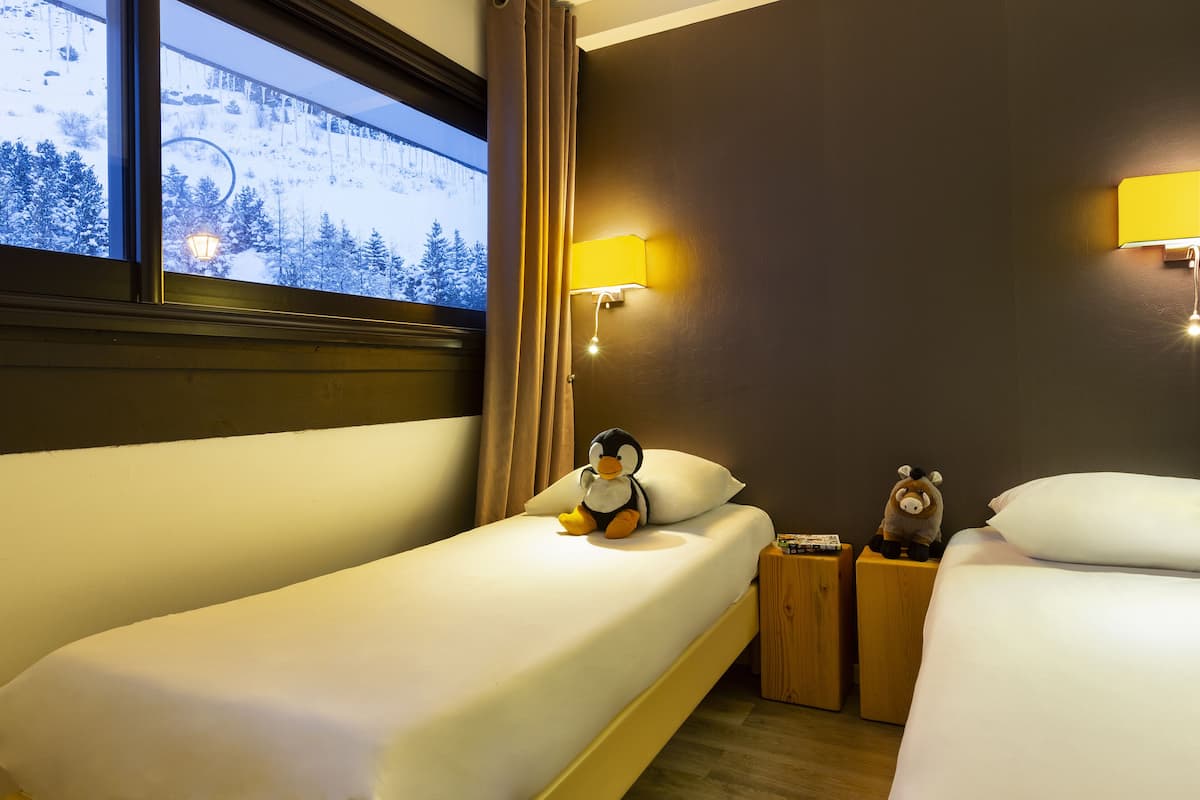 A hotel room with a bed, a nightstand, a lamp, and a window with curtains.