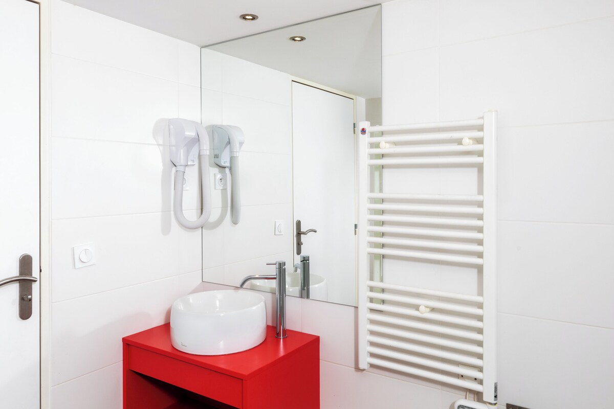 A modern bathroom with a white sink, red vanity, and a white towel rack.