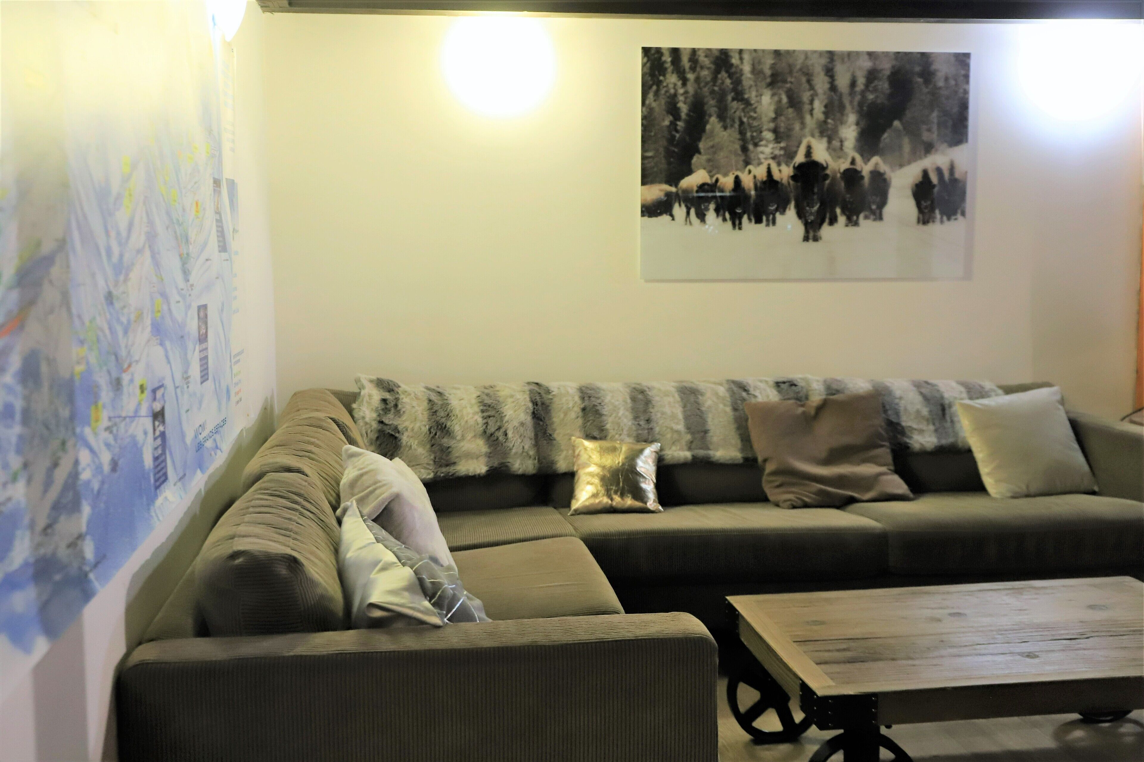 Ein Wohnzimmer mit einem Ecksofa, einem Couchtisch und einer Wand mit einer Karte und einem Schwarz-Weiß-Foto.