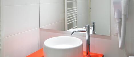A modern bathroom with a white sink on a red vanity, a mirror, and a towel rack.