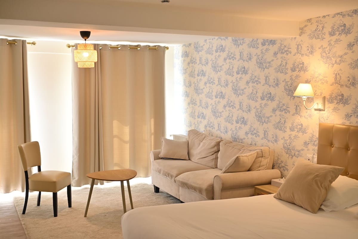 Une chambre d’hôtel avec un lit, un canapé, une chaise, une table et une lampe.