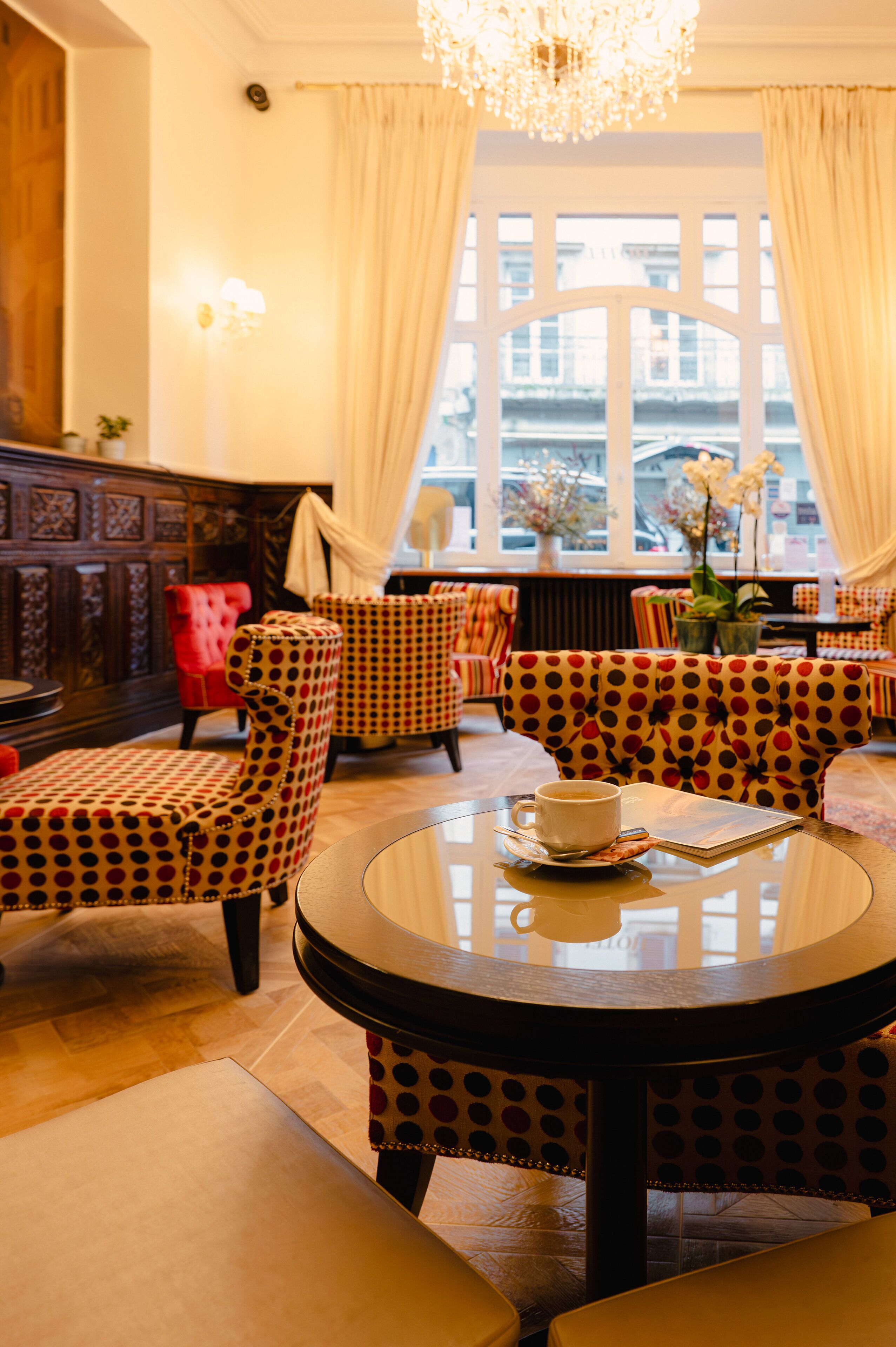 Una zona de estar acogedora con sillones estampados y una mesa redonda con una taza y un platito.