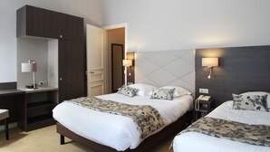 Habitación de hotel con dos camas, un escritorio y un armario.