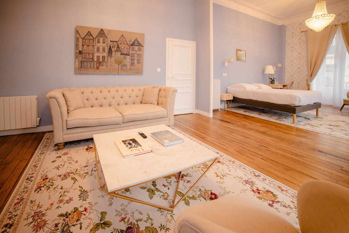 Une pièce comprenant un canapé, un lit, une table basse et un tableau accroché au mur.
