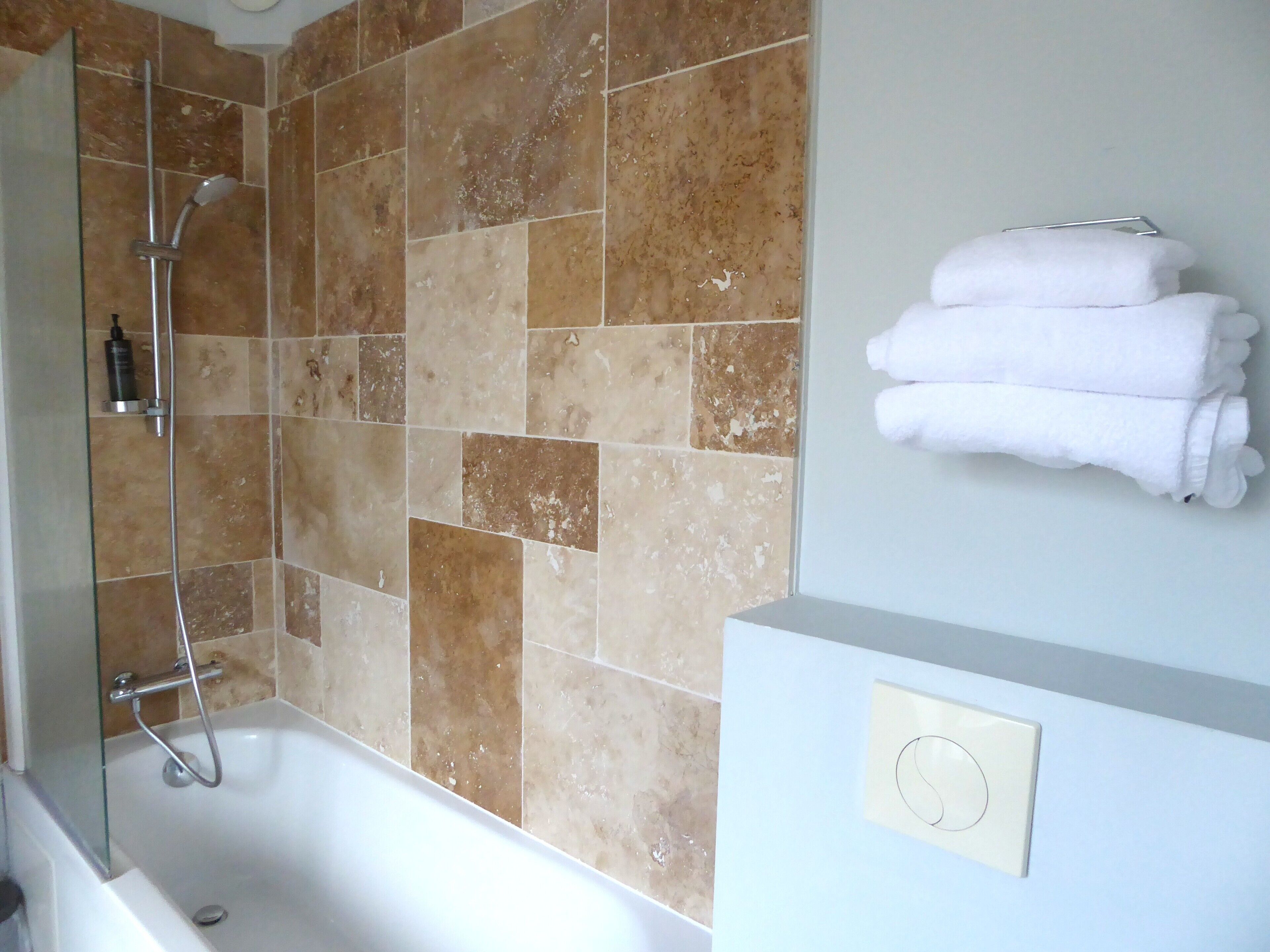 Ein Badezimmer mit Badewanne, Dusche und einem Handtuchhalter mit gefalteten Handtüchern.