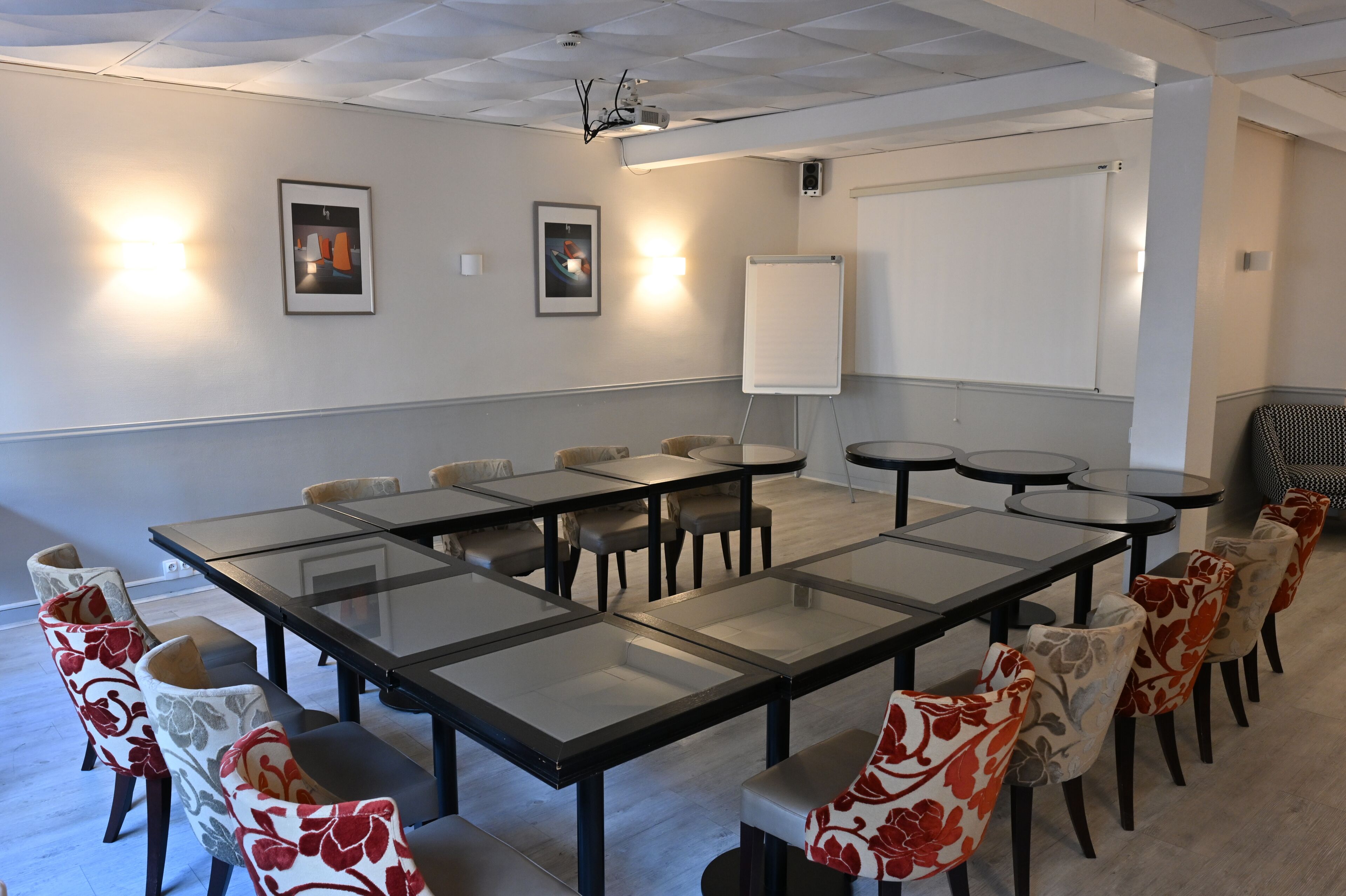 Un salón de conferencias con una gran mesa, sillas, una pizarra y cuadros en la pared.