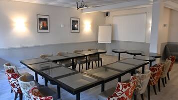 Un salón de conferencias con una gran mesa, sillas, una pizarra y cuadros en la pared.