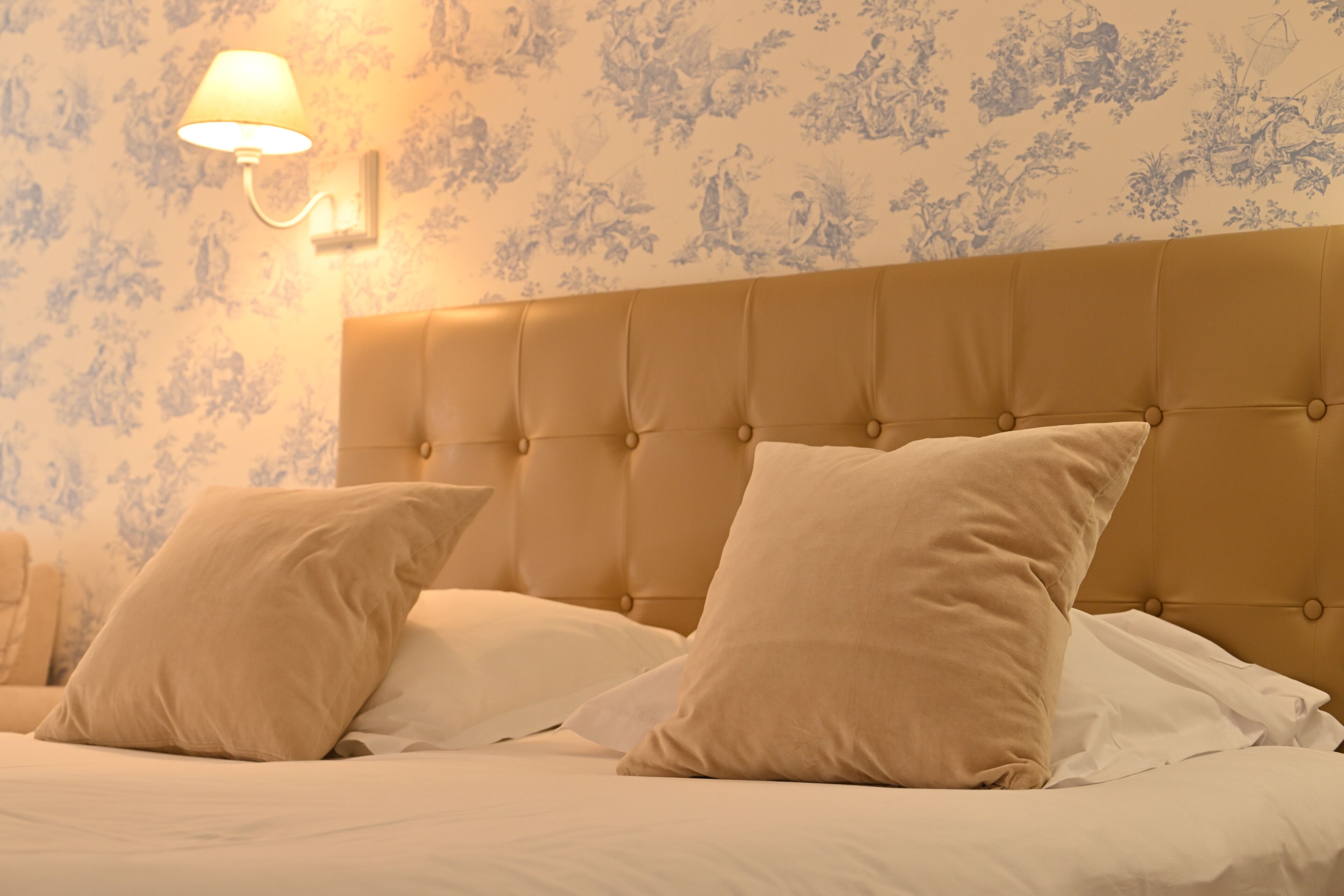 Ein Bett mit einer karrierten Kopfteil, zwei Kissen und einer Wandleuchte.