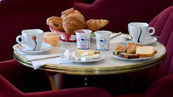 A round table with croissants, cheese, bread, and two cups of coffee.