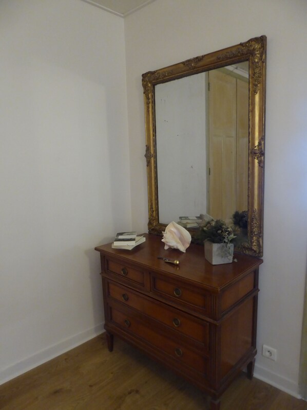 A wooden dresser with a large mirror and a few decorative items.