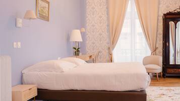 A bedroom with a bed, a nightstand, a chair, a dresser, a mirror, and a chandelier.
