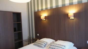 A hotel room with a bed, two bedside lamps, a wooden headboard, and a striped wall.