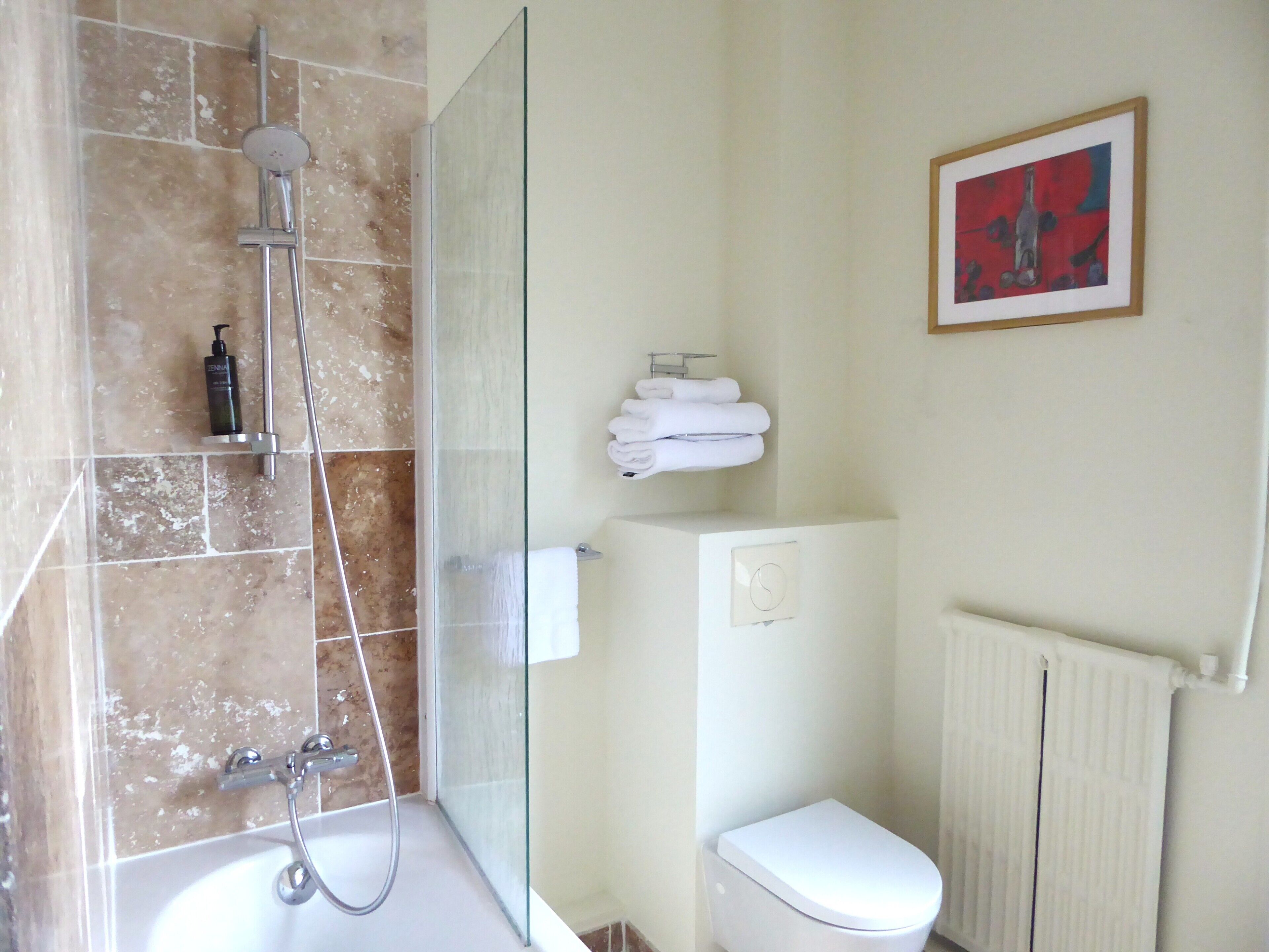 A bathroom with a glass-enclosed shower, a white toilet, and a radiator.