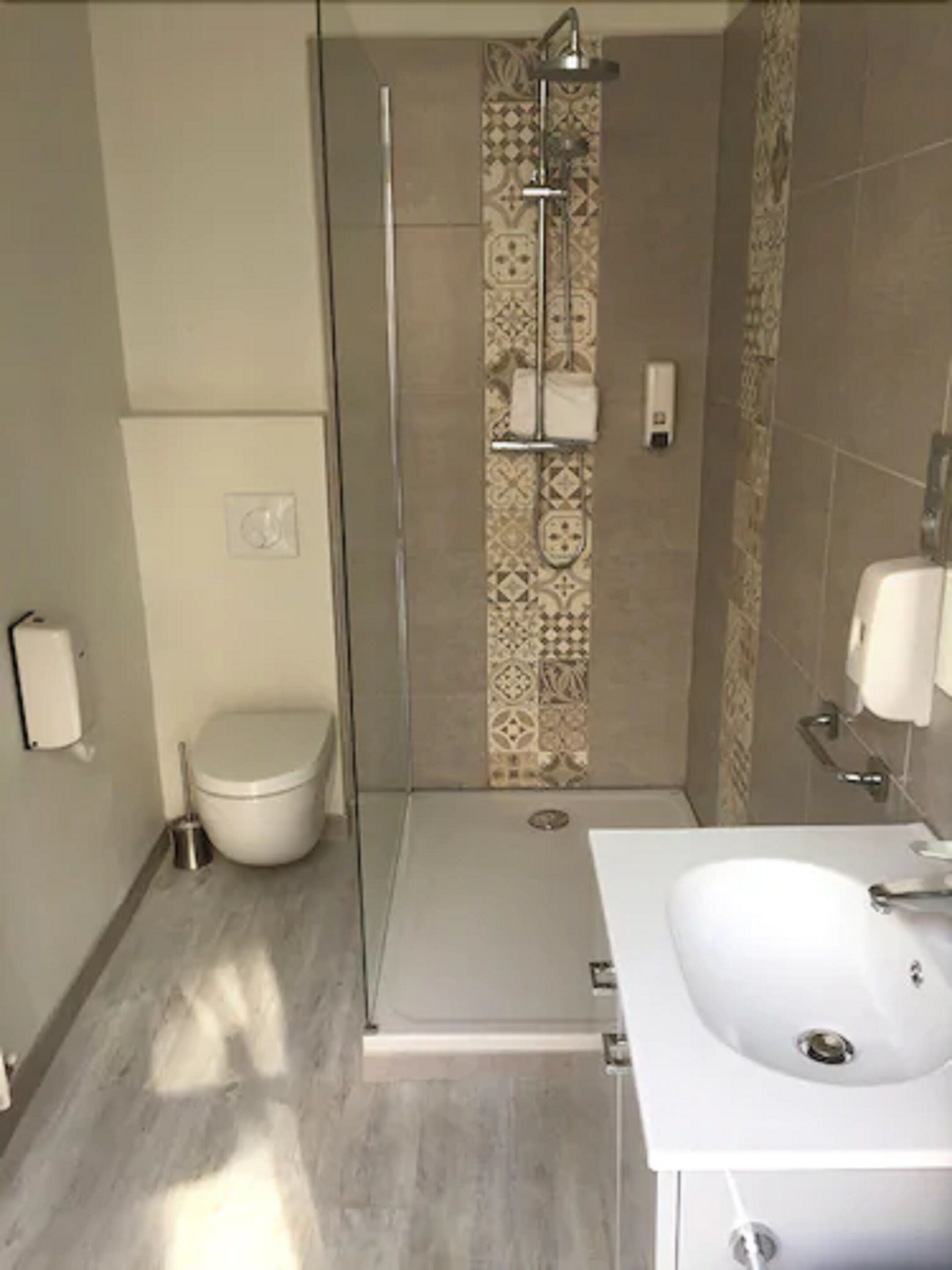 A bathroom with a toilet, a shower with a glass door, and a sink with a mirror.