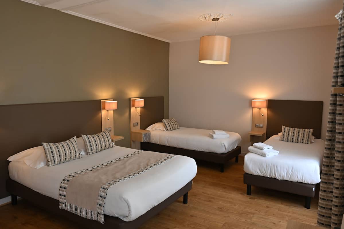 Une chambre d’hôtel avec trois lits, chacun doté d’une tête de lit et de lampes de chevet.