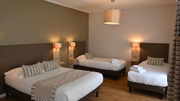 Habitación de hotel con tres camas, cada una con cabecera y lámparas de noche.