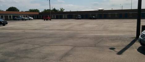A large parking lot with several cars and a building in the background.