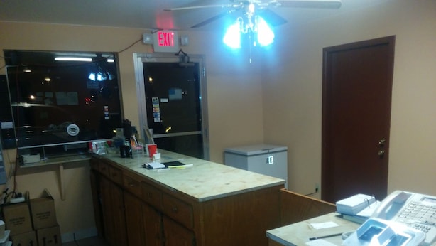 A kitchen with a countertop, a refrigerator, a ceiling fan, and a window.