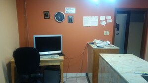 A small office with a desk, computer, chair, and a clock on the wall.