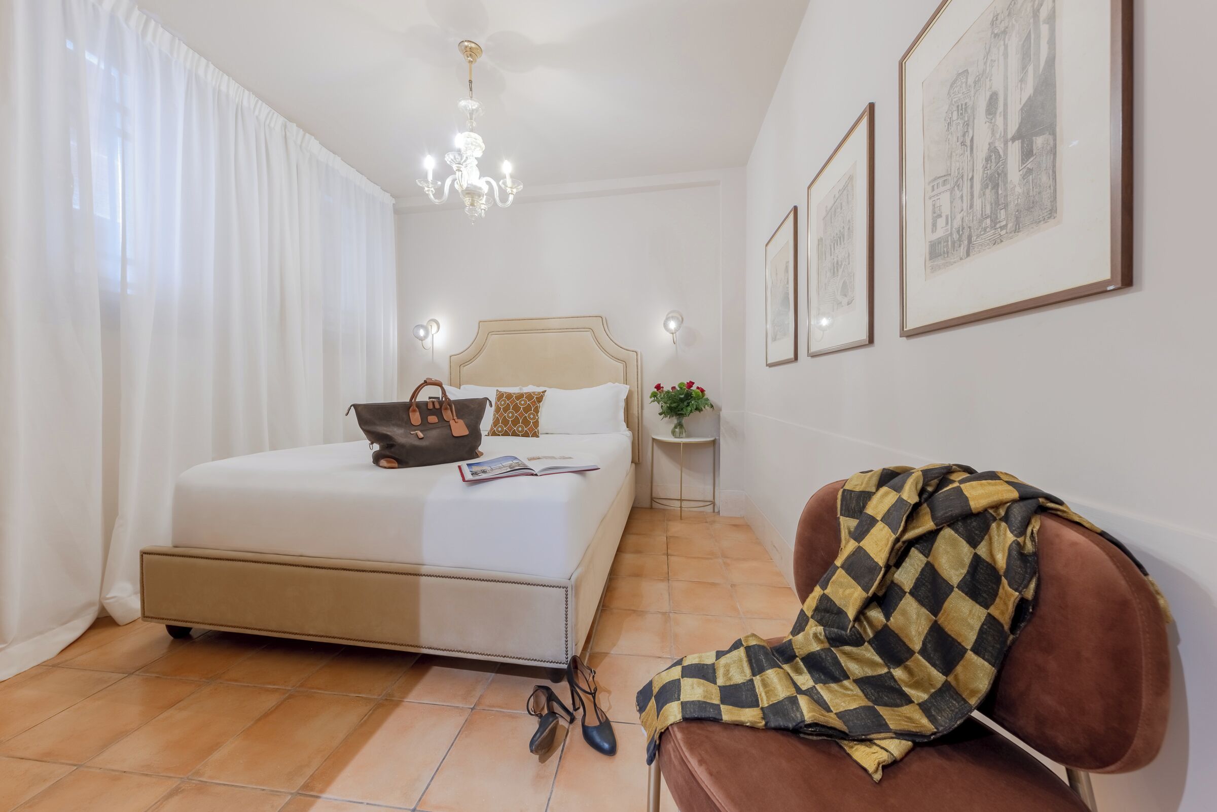 Une chambre à coucher avec un lit, une table de chevet, une chaise et des tableaux encadrés accrochés au mur.