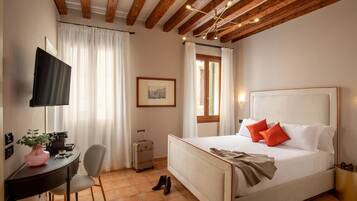 Una habitación de hotel con cama, escritorio, silla, televisor y ventana con cortinas.